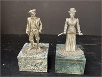 TWO PEWTER GOLFING STATUES ON GREEN STONE BASES