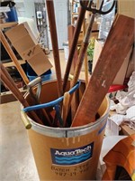Barrel full of assorted tools, spade, hoe, saw
