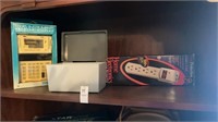 Shelf of surge protector, old calculator, and box
