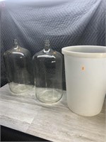 2 large glass jugs, plastic garbage can