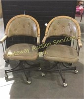 Two kitchen chairs on wheels . Seat has a rip.