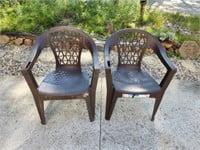 Two brown plastic molded stackable patio chairs