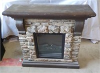 Electric fireplace with fake stone and mantle.