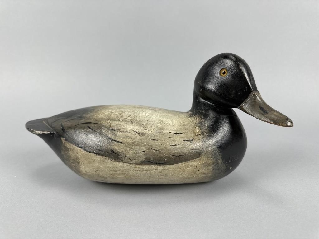 Rare Charles Perdew Bluebill Drake Duck Decoy.Henry, IL, glass eyes, hollow body, strong original paint by Edna Perdew, excellent patina with wonderful blending & subtle combing detail on back, very light gunning wear with some rubs & small imperfections, incredible form with head being turned slightly right, a small amount of glue was utilized to secure & stabilize the head, this drake is considered by many collectors as one of the finest examples known, features Haertel Collection stamp on bottom, Harold Haertel Collection, 12"L, est. 14,000 - 18,000