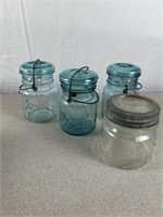 Glass canning jars with lids, mostly Ball brand.