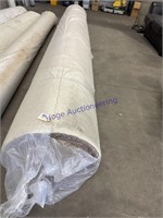 LARGE ROLL OF CARPET WRAPPED IN PLASTIC ON FLOOR