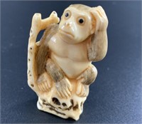 Antique mammoth netsuke of a monkey sitting in a t
