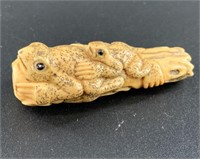 Antique mammoth netsuke of two frogs laying on a l