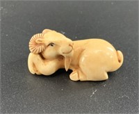 Antique mammoth netsuke of a small ram curled up,