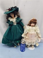 2 porcelain dolls the green dress has a stain and