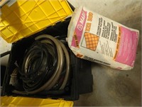 Tote of hoses and bag of grout