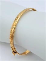 A 9 K yellow gold bangle with a decorative engravi