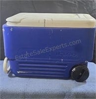 Igloo cooler on wheels. Spattered with grey paint.