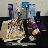 Group of paint brushes, watercolors, and other