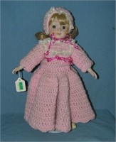 Porcelain doll with pink wool dress and hat and bu
