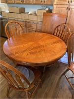 Wooden dining table has extra leaf and six chairs