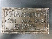 Cast iron wall plaque that says "Hair Cut & Shave