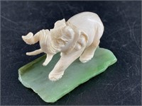 Antique ivory carving of an elephant on a green ja