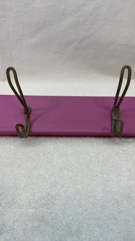 Antique coat hooks on a purple board