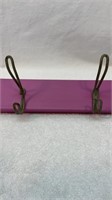 Antique coat hooks on a purple board