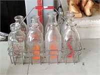8 various milk bottles in wirey carrier