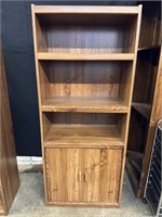 Tall light brown bookshelf with cabinet