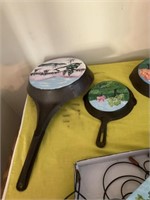 Two decorated fry pans, one cast-iron