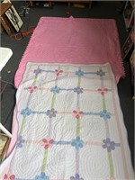 2 pink and flowered quilted blankets