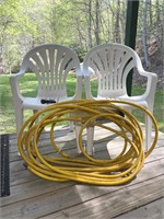 2 Plastic Deck Chairs and Yellow Garden Hose