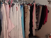 All the women's clothes on the rack. Skirts pants