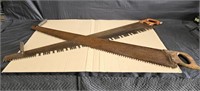 Two antique two-man logging saws with wooden