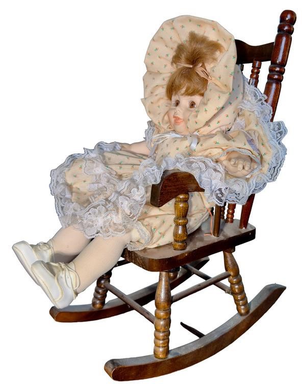 Doll in wooden rocking chair. Doll is "Tina" by
