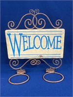 Metal “Welcome” sign with rings for storage