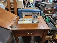 White sewing machine in table with accessories
