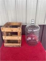 Large glass wine jug in crate