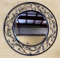 Large round beveled mirror surrounded by metal